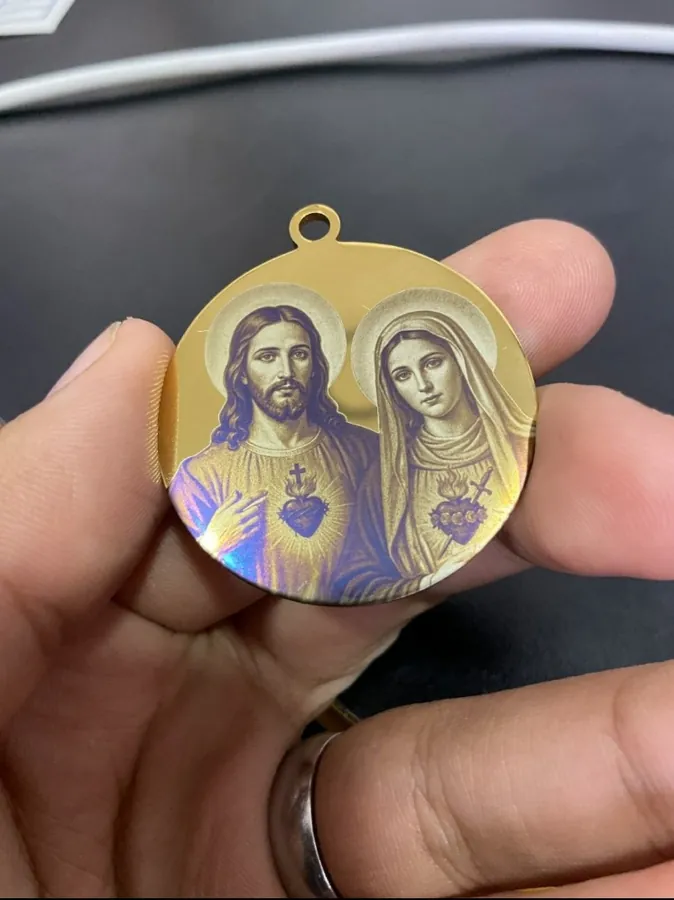 Fotografía real de una medalla dorada con los Sagrados Corazones de Jesús y María